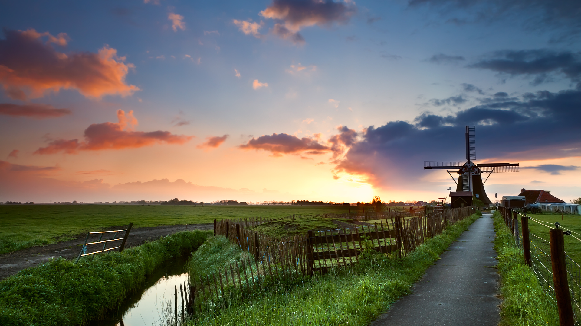Landelijk gebied Nederland met windmolen in de achtergrond tijdens zonsondergang